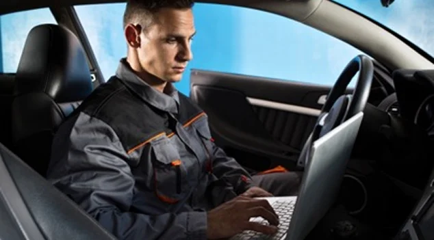 Un mécanicien automobile utilise un ordinateur portable à l'intérieur d'une voiture à Virazeil près de Marmande dans le Lot-et-Garonne 47